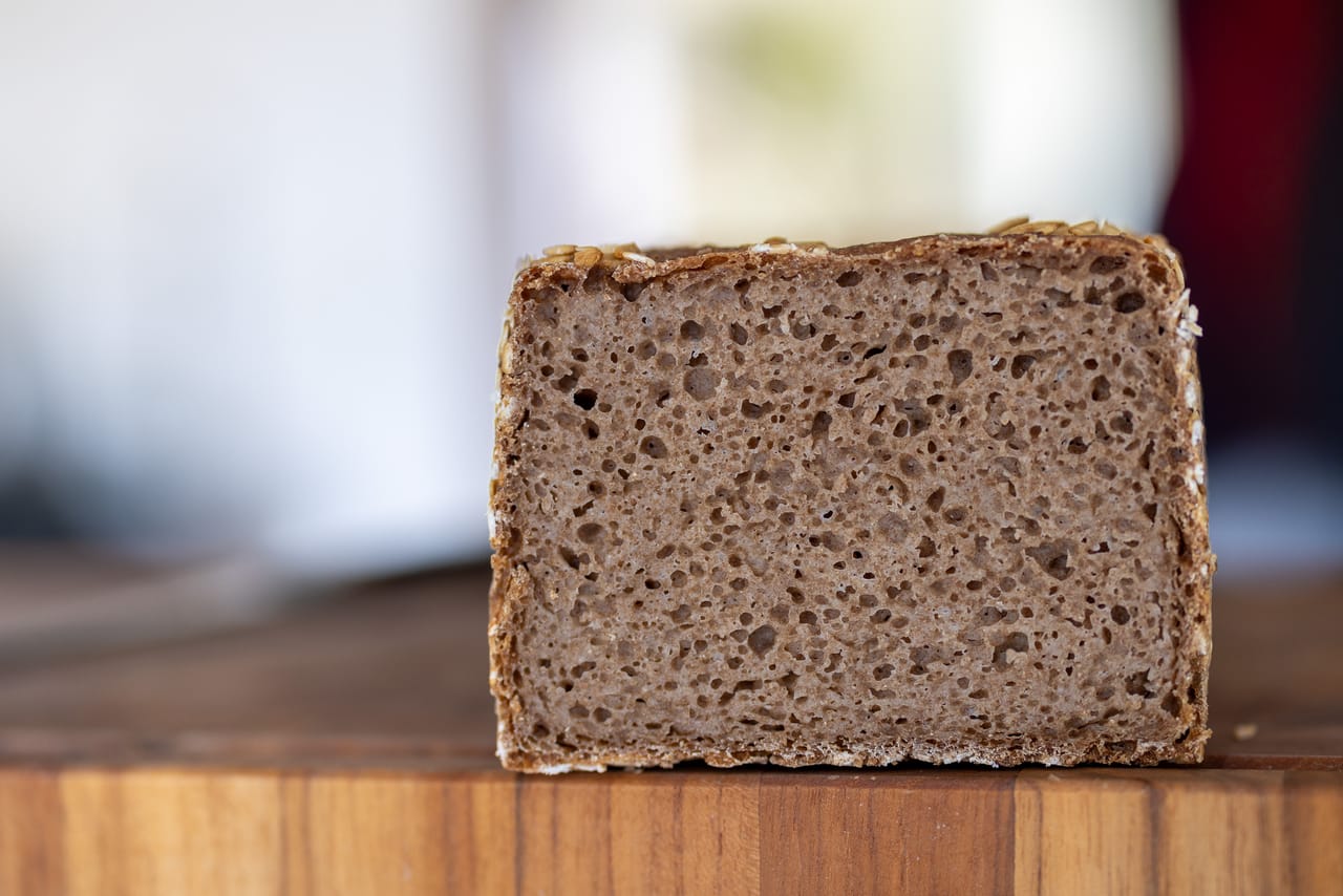 A cut rye pan loaf with a seed crust and an even, dense crumb